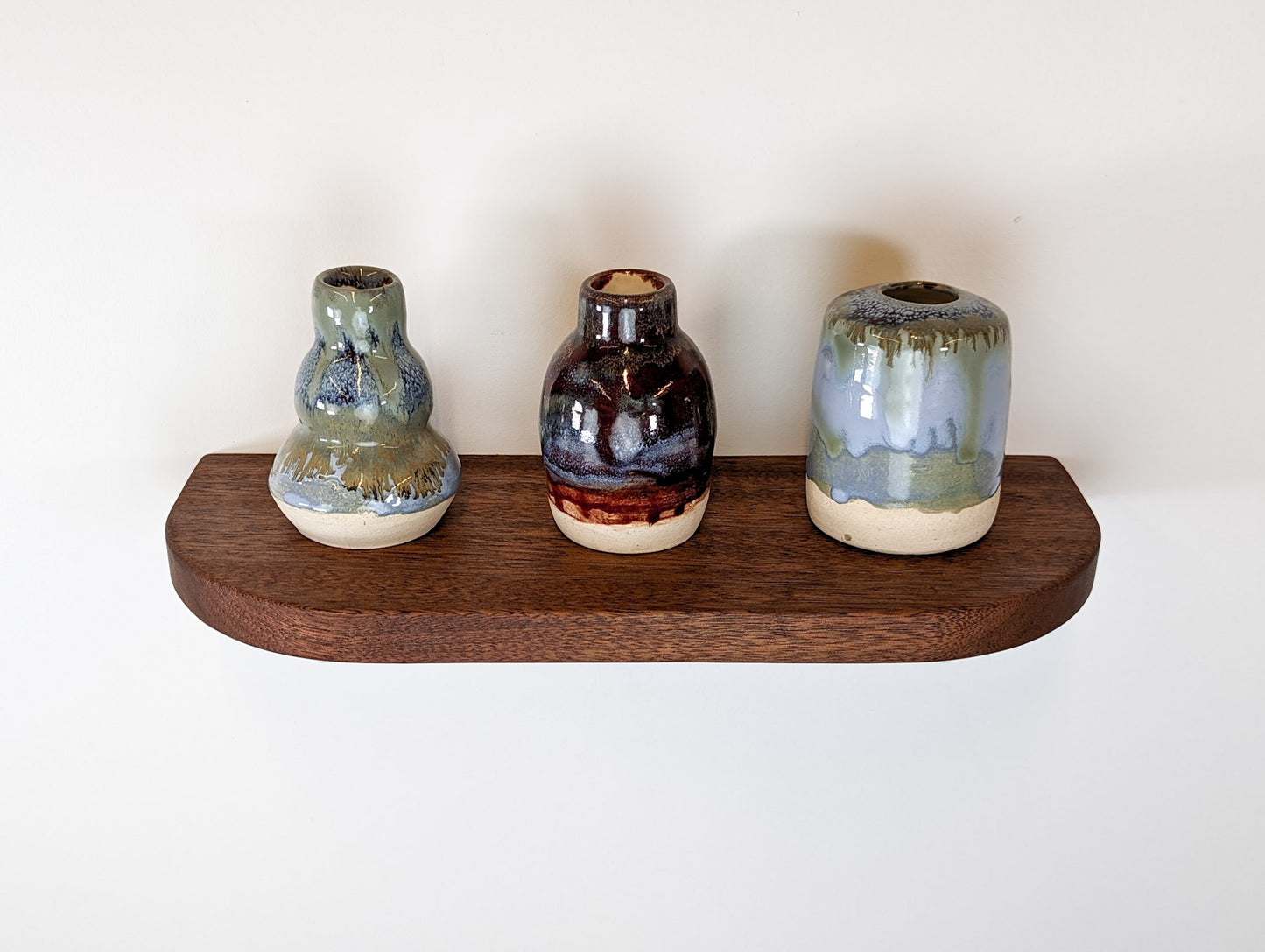 Top view of a mahogany floating shelf with three vases as decor