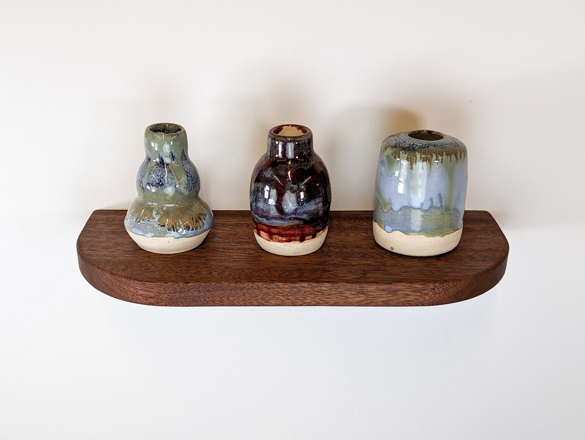 Top view of a mahogany floating shelf with three vases as decor