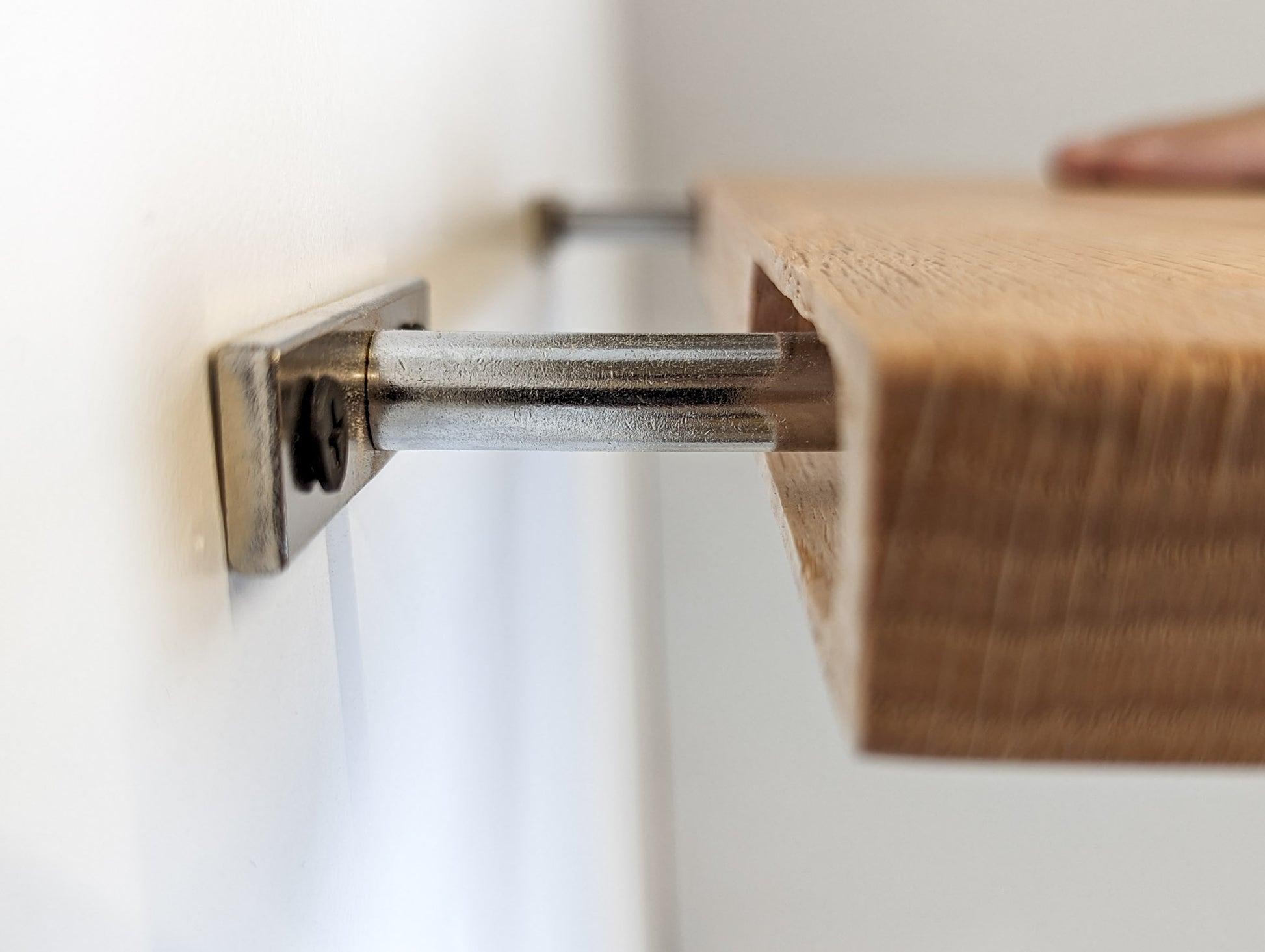 Close up side view of the oak shelf sliding onto the two metal brackets