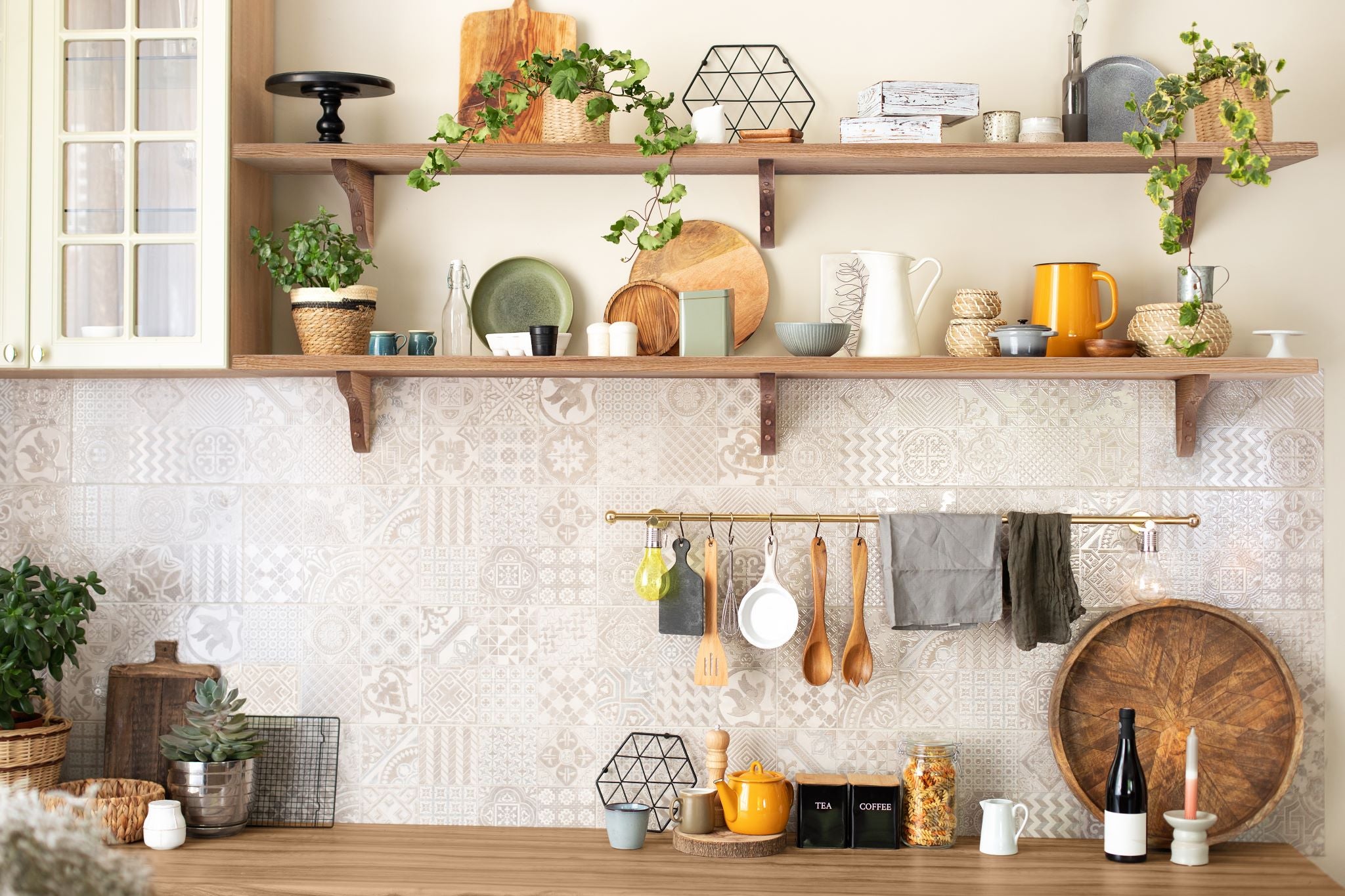 Two oak kitchen floating shelves with items on them installed next to a cupboard. 
