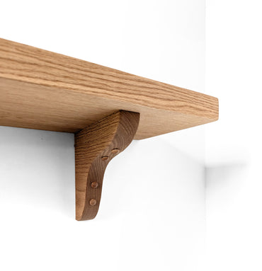 Zoomed in underview of oak brackets holding up a heavy duty shelf. 