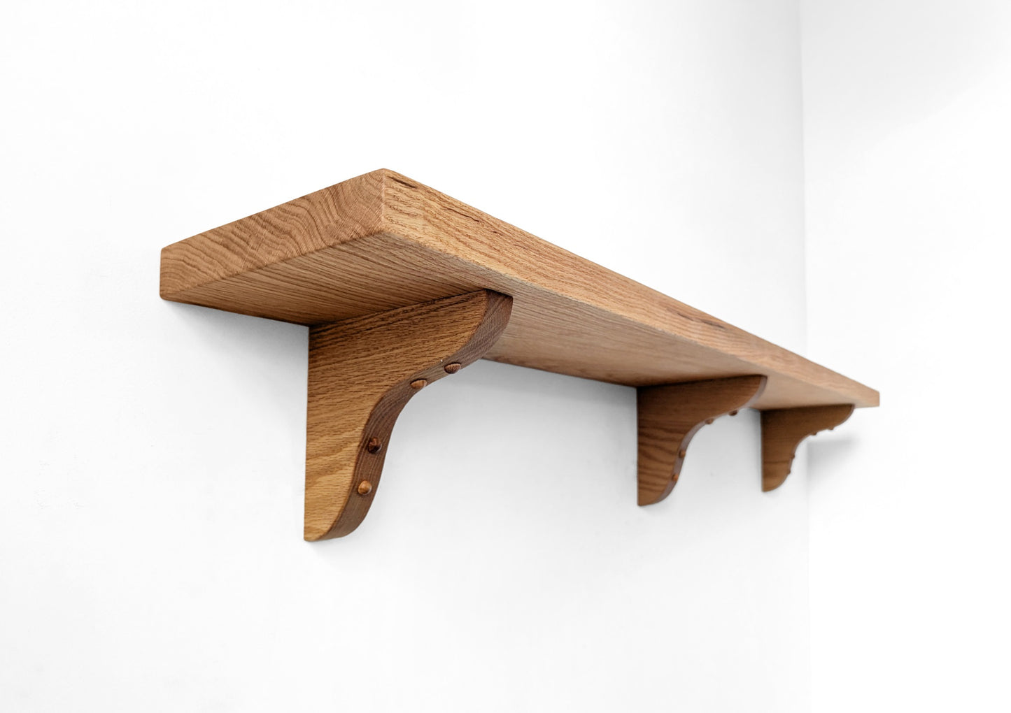 Three wood brackets installed on a wall.
