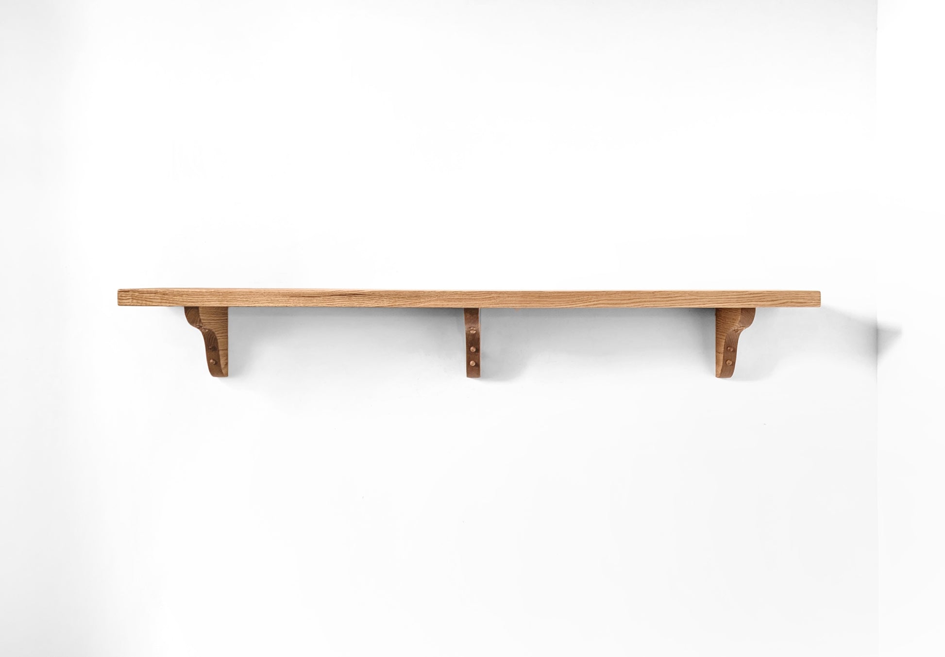 Front view of a thick heavy duty wooden shelf with three curved wood brackets.