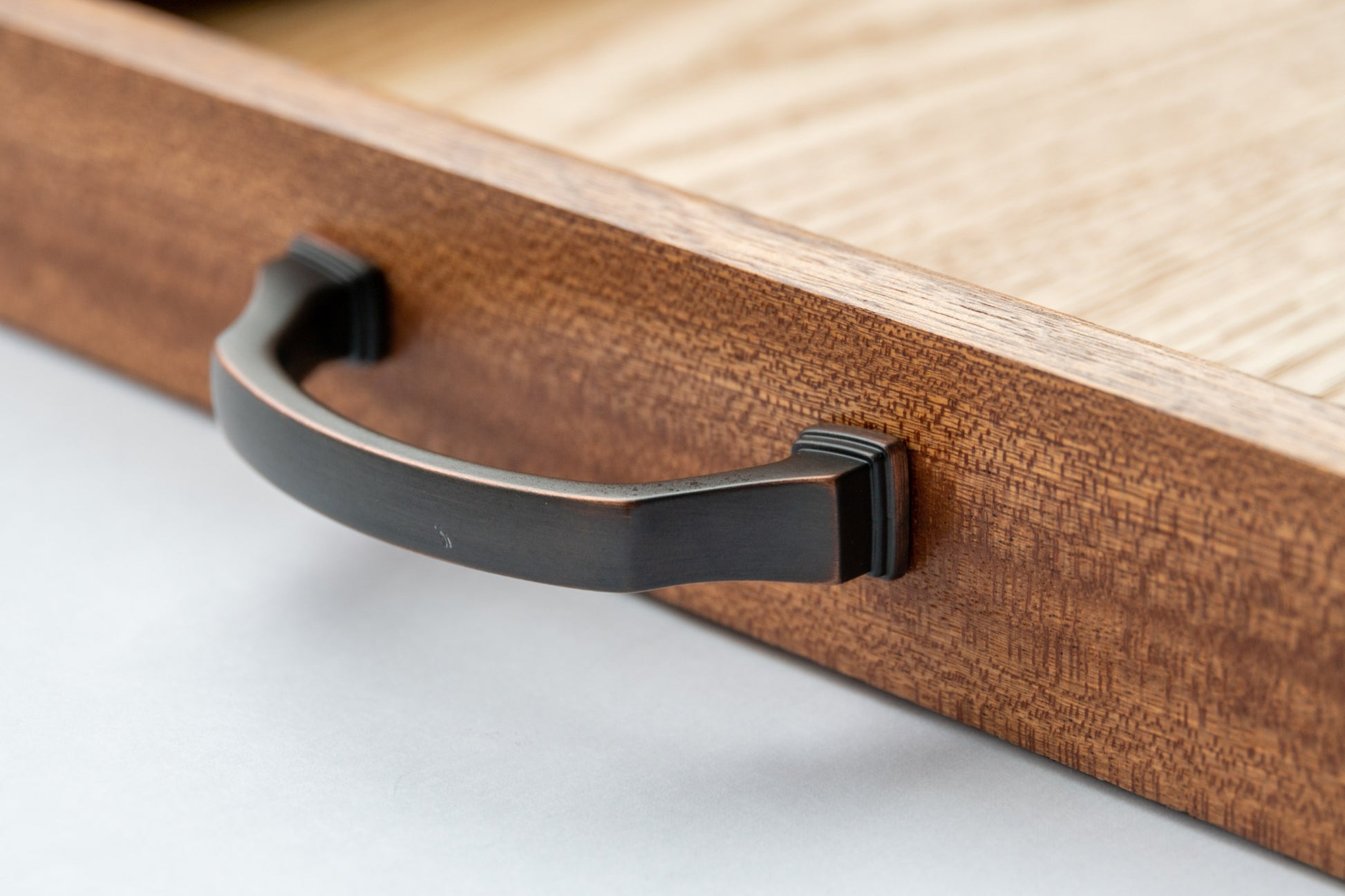 A close-up of the dark brass handles of our Luxury Serving Tray with Full Grain Leather. The black handle features a copper sheen and is securely installed to ensure care-free handling.