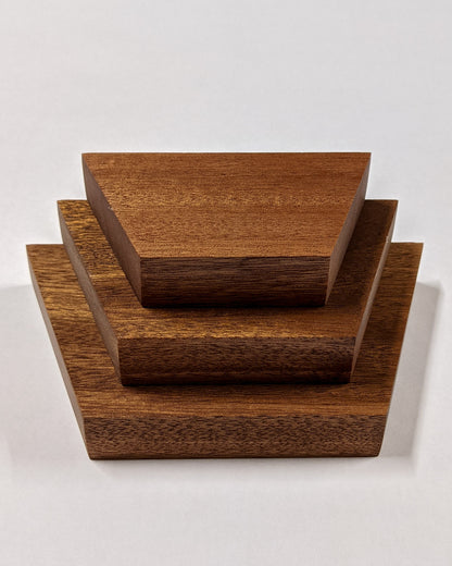 Three trapezoid floating shelves in oak sit on top of the other in varying sizes from largest to smallest.