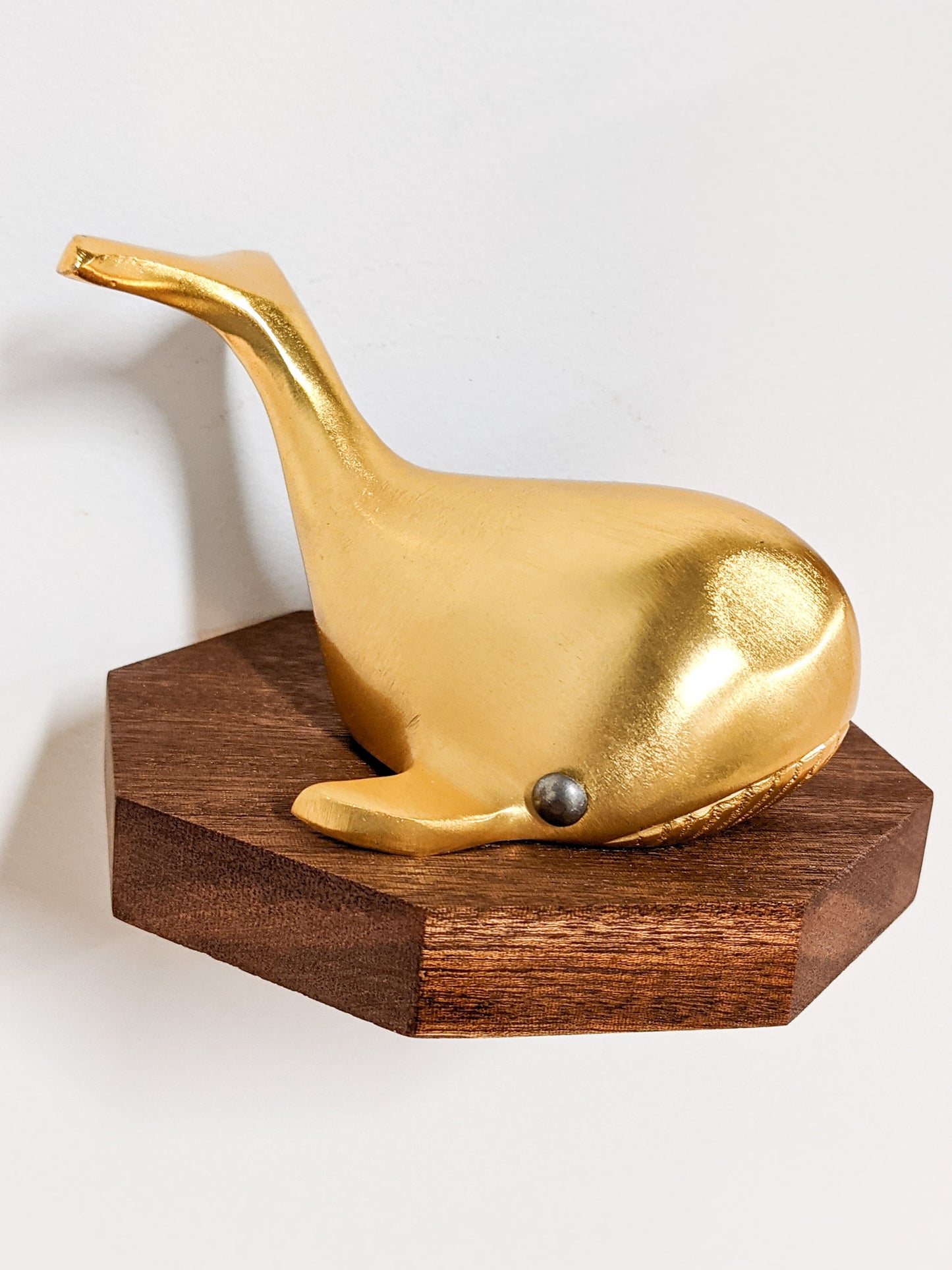 A small octagon floating wood shelf is installed on the wall. Atop it sits a golden whale.