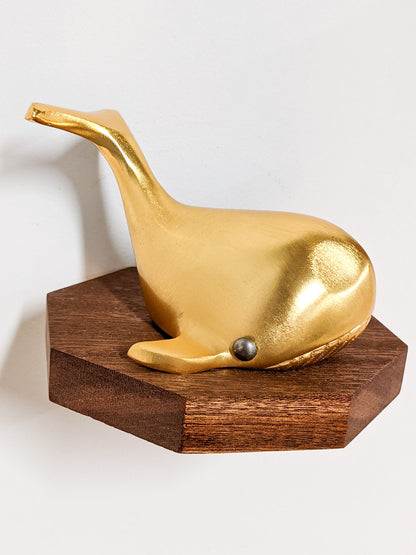 A small octagon floating wood shelf is installed on the wall. Atop it sits a golden whale.