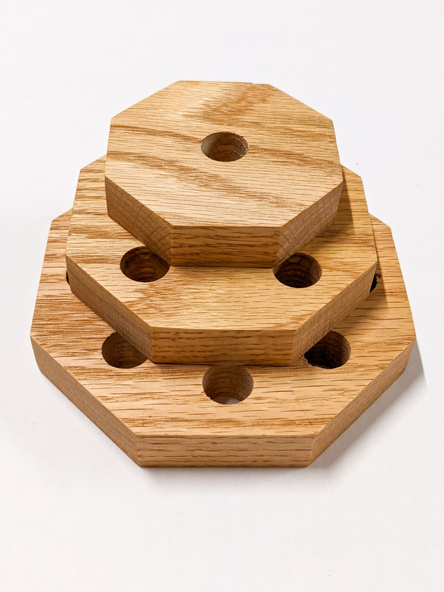 A set of three oak octagon propagation shelves sit one on top of the other with the largest at the bottom and the smallest on top.