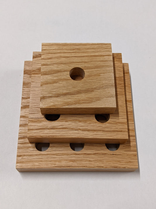 A set of three oak square propagation shelves sit one on top of the other with the largest at the bottom and the smallest on top.