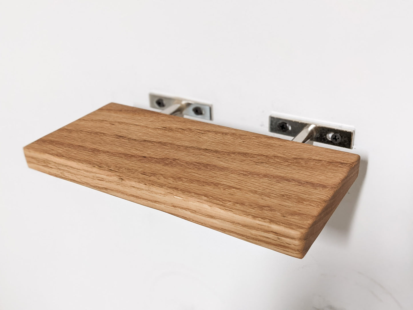 A minimalist oak wooden floating shelf is easily installed with two silver rods for a clean and invisible floating appearance.