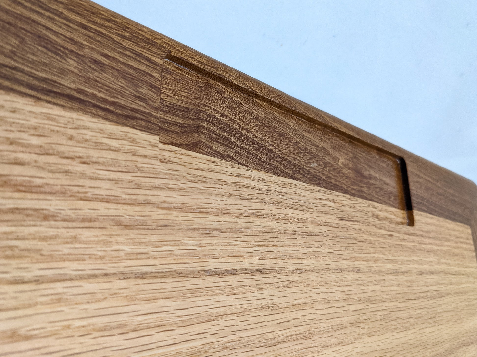 A close-up of the rectangular pen and pencil holder of our Wooden Writing Lap Desk. The pencil holder features mahogany and oak wood that meet halfway in a dazzling display of natural grain and color.