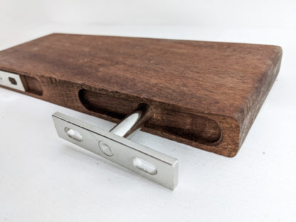 The back of a medium floating shelf in mahogany demonstrating how two silver brackets securely stabilize the floating shelf to the wall.