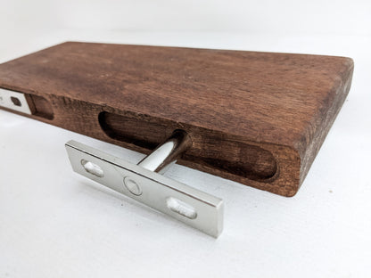 The back of a medium floating shelf in mahogany demonstrating how two silver brackets and screws attach the shelf to the wall to make it appear as if it is floating.