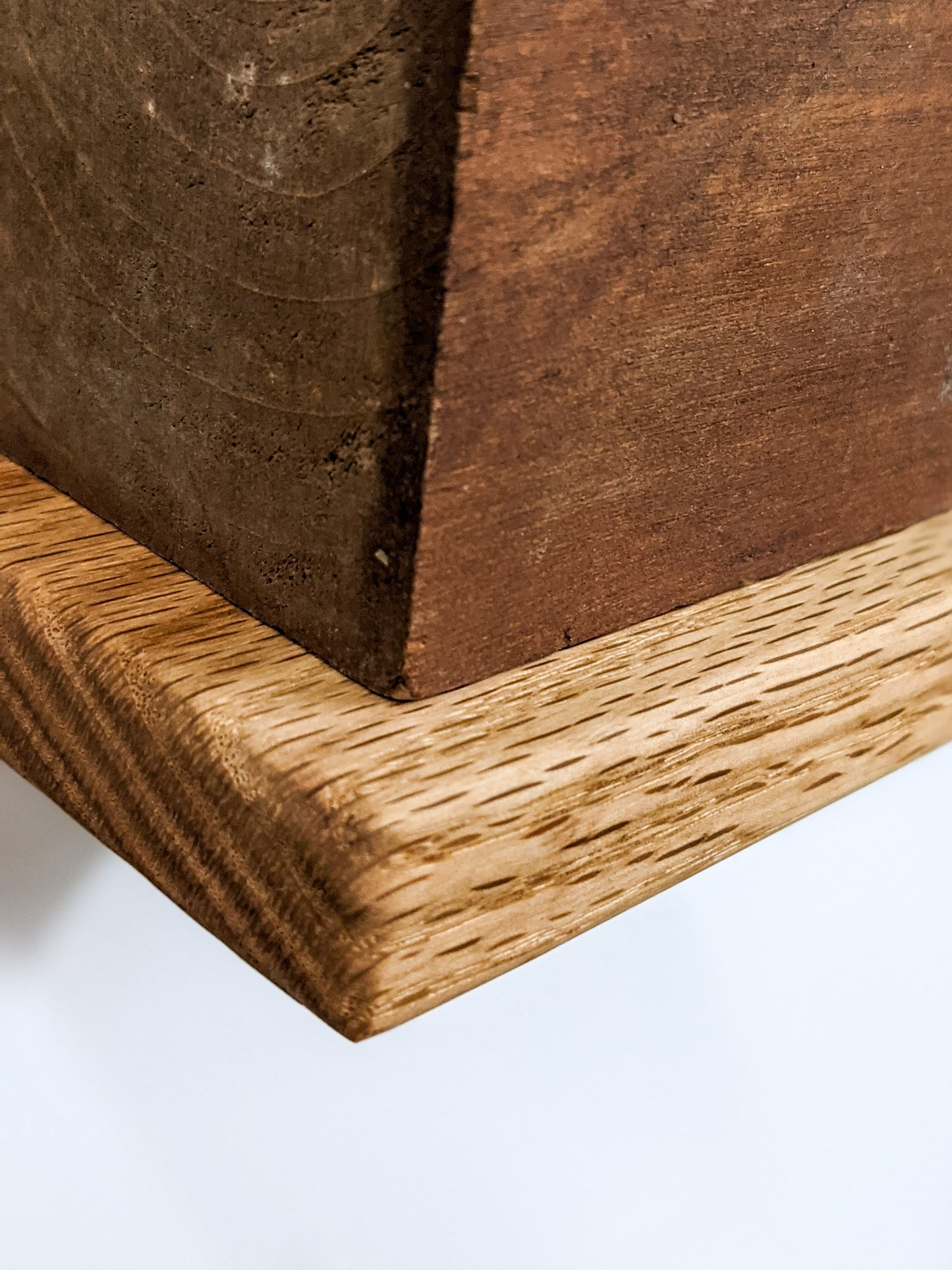 A small square floating shelf with soft rounded edges; the light oak is contrasted with the brown of a mahogany square planter that sits atop.