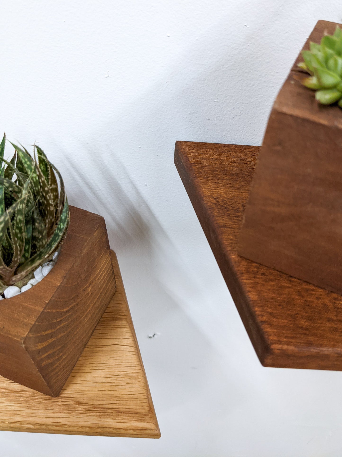 A top down view of the oak and mahogany rhombus floating shelves, the contrast in color between the dark reddish brown of the mahogany floating shelf and light oak floating rhombus shelf is highlighted.